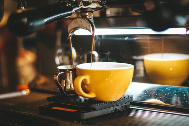 a coffee maker making a shot of espresso in a yellow mug